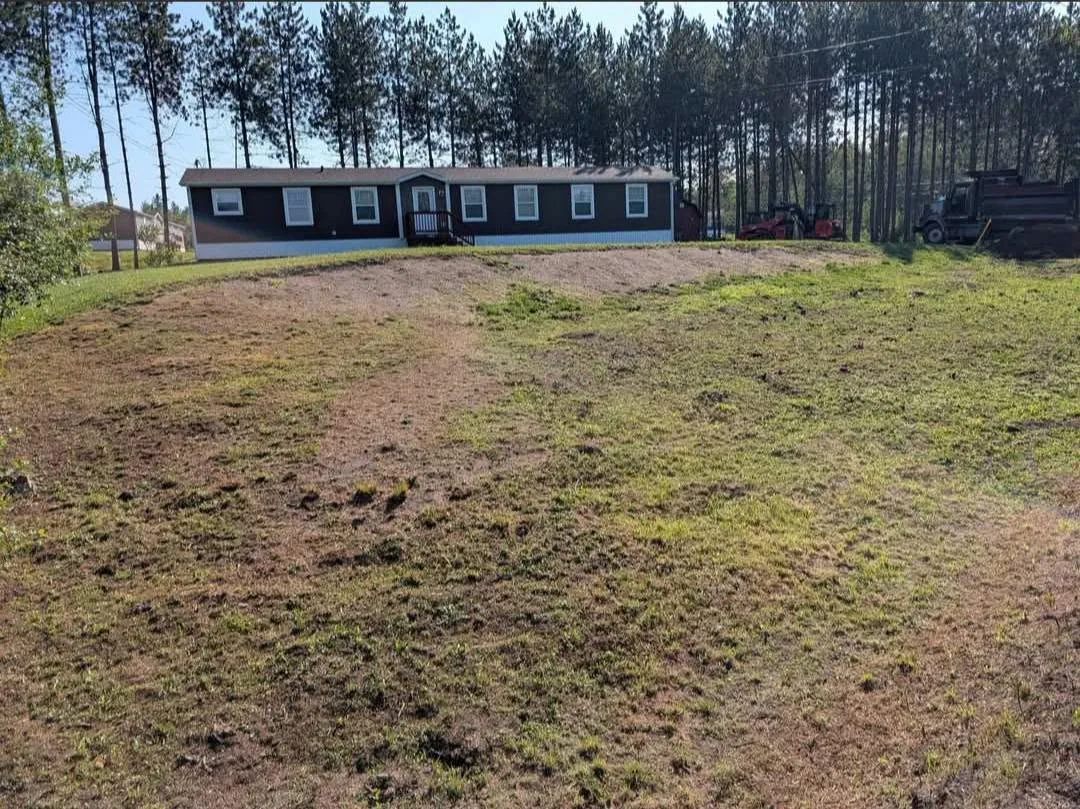 Uneven patchy front lawn below a long brown home before the property improvements